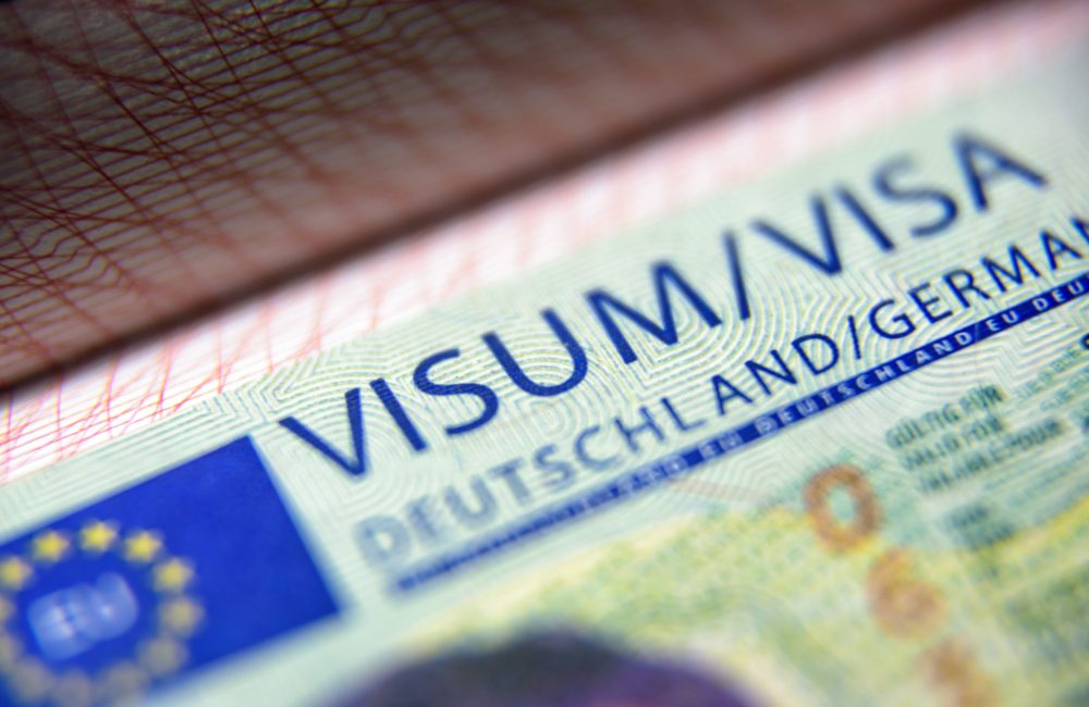 Visa stamp in passport close-up. German visitor visa at border control. Macro view of Schengen visa for tourism and travel in EU. Document for multiple entry. Legal immigration to Germany and Europe.